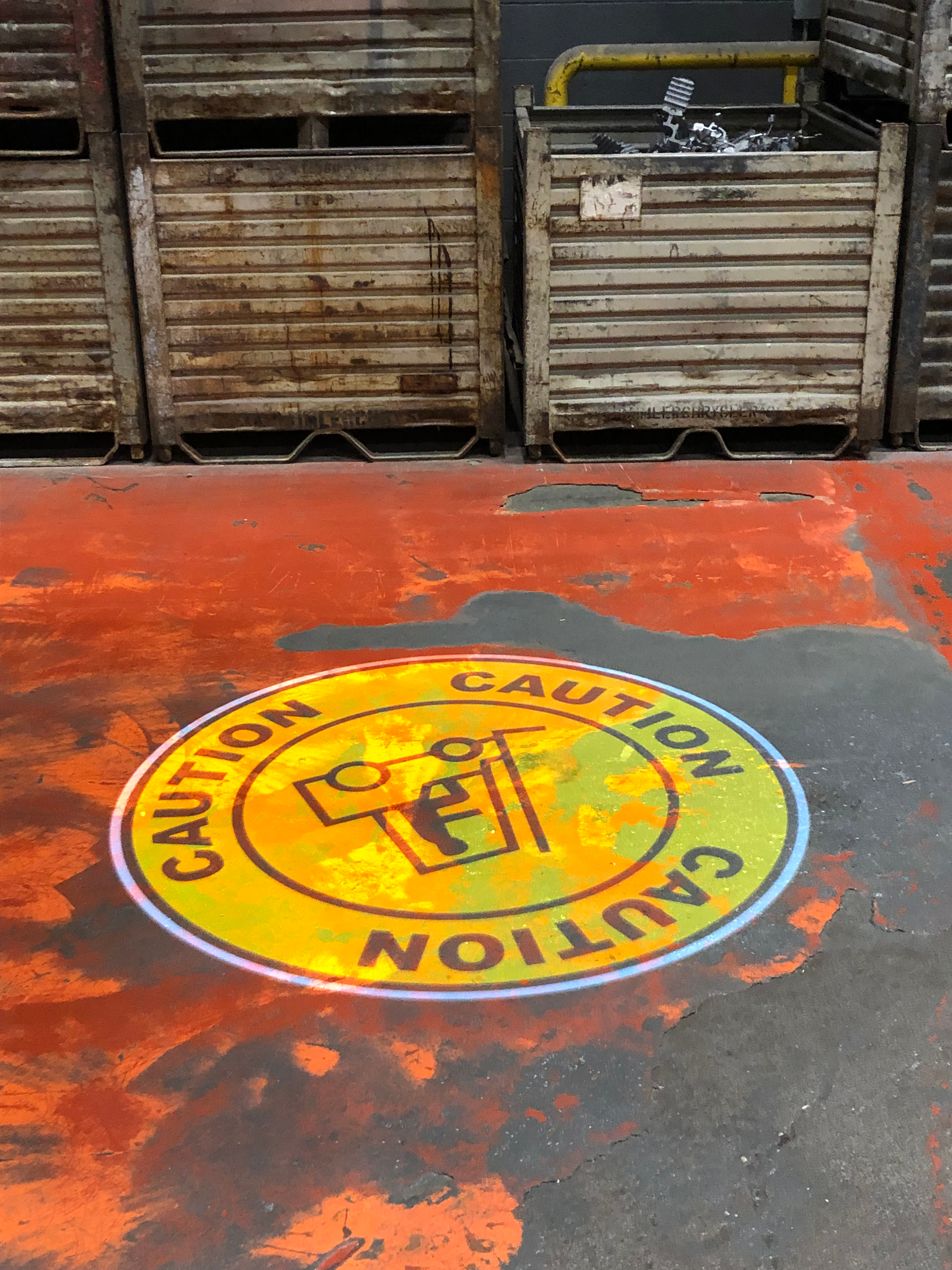 SafetyCast "Caution" warning sign projected onto the worn out warehouse floor